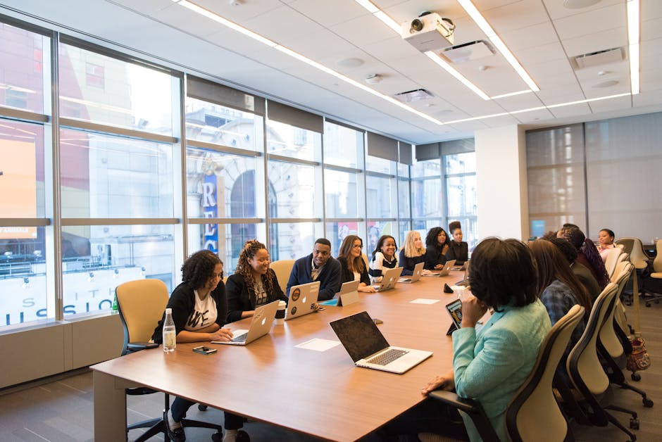 A professional working in a public sector unit office, surrounded by colleagues and engaging in a meeting