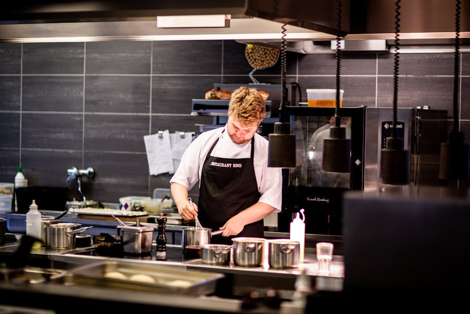 A realistic image depicting a busy restaurant kitchen with chefs working together, communicating, and preparing dishes. The kitchen is organized and bustling with activity.