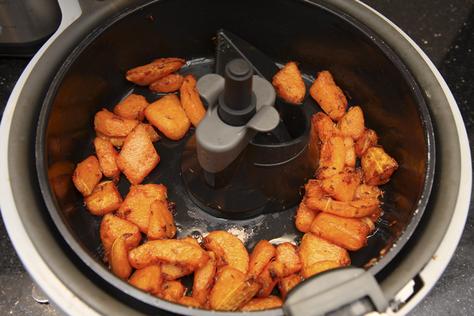 An air fryer cooking a variety of foods like vegetables, meats, and fruits