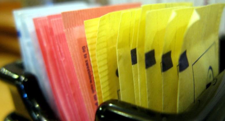 A collection of different colored packets containing various artificial sweeteners.