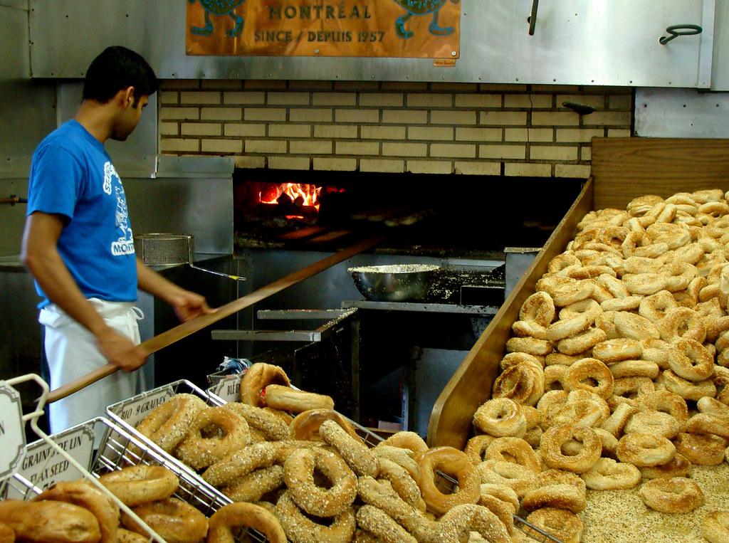 The cozy interior of a bagel shop with wooden shelves displaying various types of freshly baked bagels