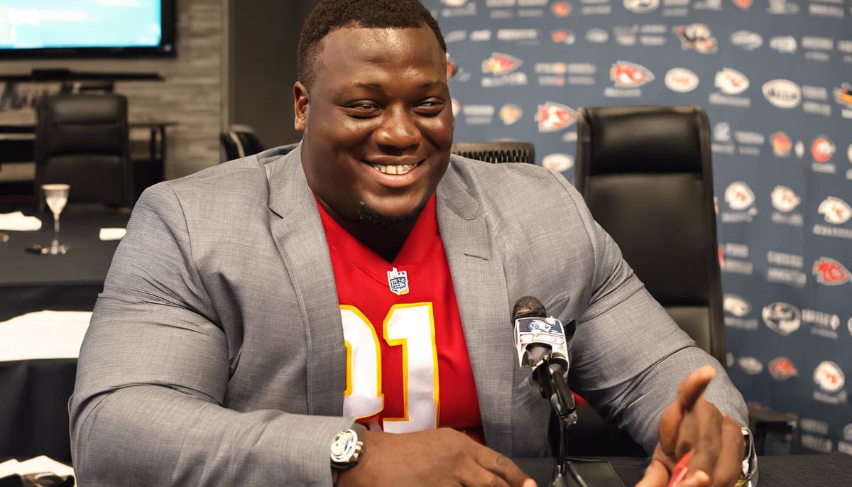 Chris Jones smiling and shaking hands with Kansas City Chiefs executives after signing his contract extension.