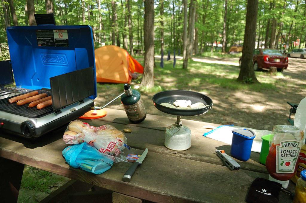 A compact and organized outdoor cooking setup for glamping, featuring a portable stove, cookware, and camping utensils.