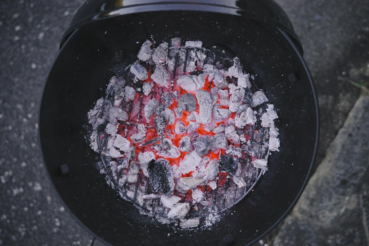 Glühende Holzkohle mit einer dünnen Ascheschicht auf einem Grill