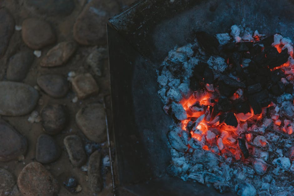 Glühende Holzkohle wird aus einem Metallbehälter entnommen