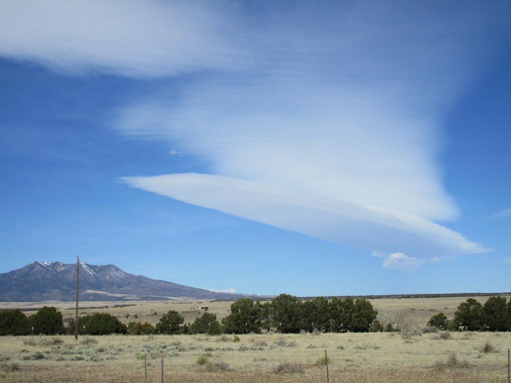 Smooth, lens-shaped lenticular clouds over a mountain range