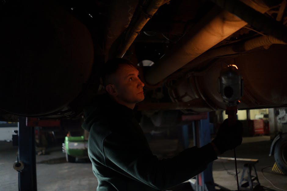 A mechanic examining the underside of a car on a lift during an MOT test