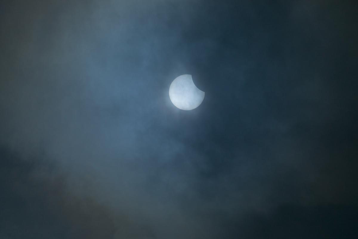 An image showing a partial solar eclipse obscured by clouds, emphasizing the impact of cloud coverage on eclipse visibility