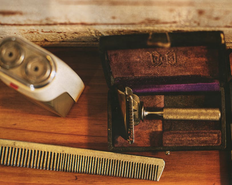 A realistic image showcasing various vintage razors, brushes, and artisanal shaving soaps and creams on a wooden countertop