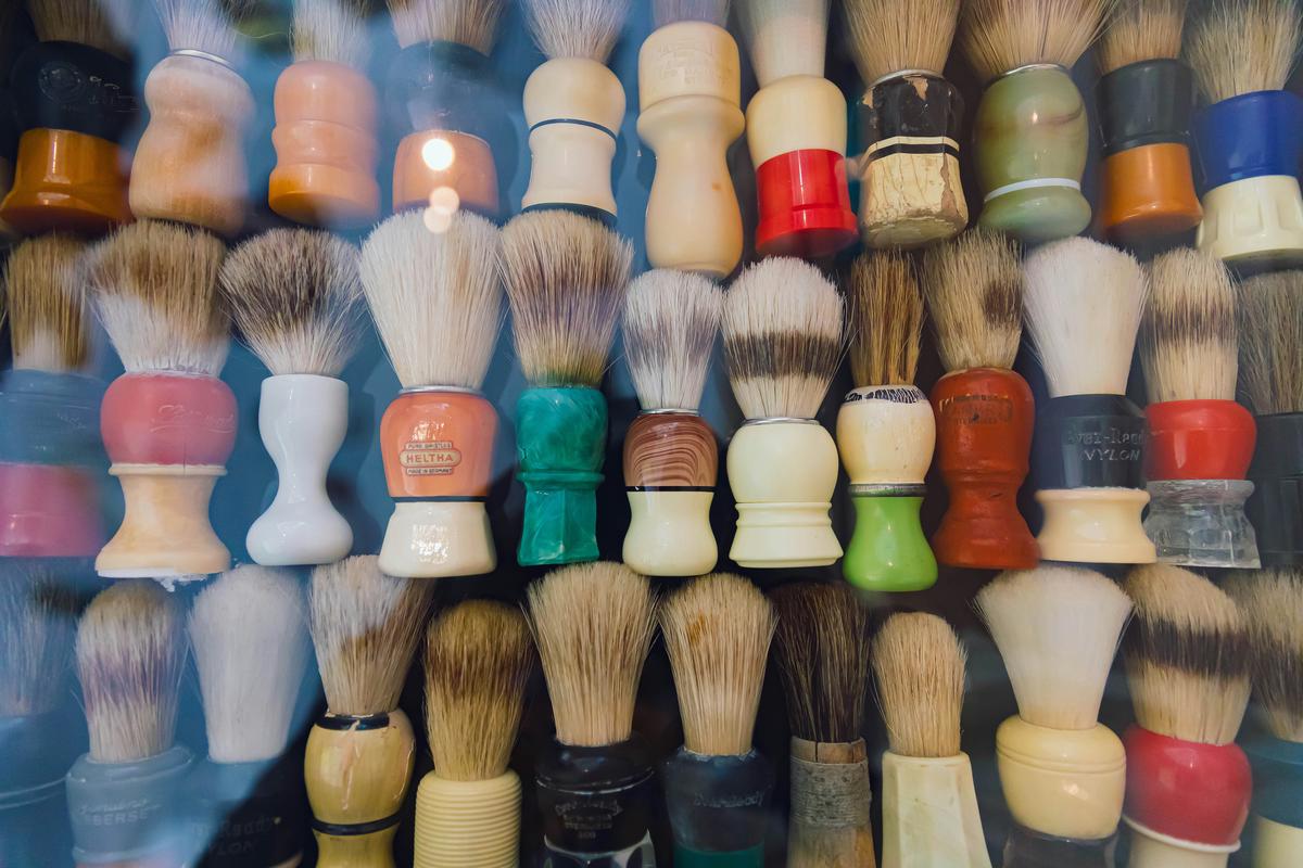 A close-up image of a traditional wet shaving set including a safety razor, shaving brush, and artisanal soap on a wooden countertop